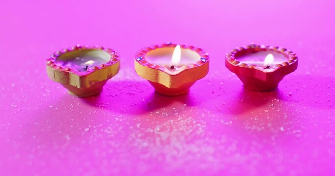 Close up of burning colourful candles celebrating diwali on purple background