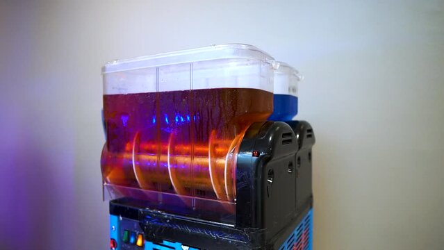slushy machine spinning red liquid sirup freshly put in to mix into frozen drink isolated with white background placed indoor for event to treat guests slow motion