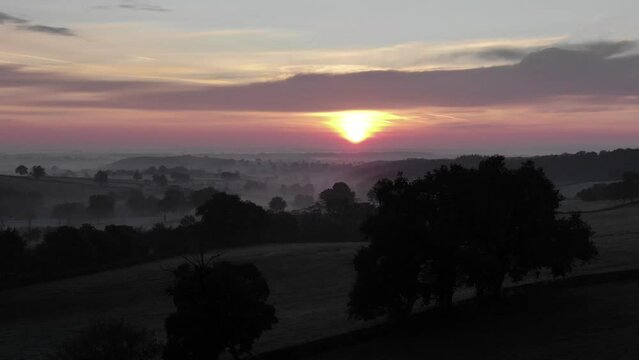 Drone flying over deserted fields with bright sun at dusk in background, Uchon in France. Aerial panoramic view