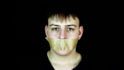 Person Placing Tape Over Mouth of Young Man, Slow Motion. Kidnapping or Free Speech Concept