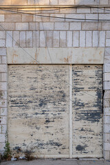Old Rusty White Metal Garage Door in a White Stone Wall