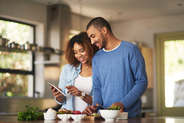 Using a step by step online recipe. Shot of a happy young couple using a digital tablet while...