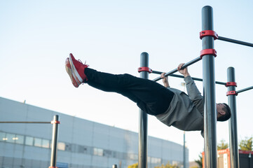 Young caucasian man doing parallel bars exercise outdoors. 
