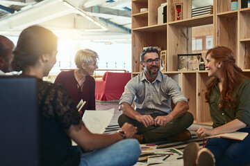 Fototapeta premium I like this business environment we have. Cropped shot of a group of business colleagues in the office sitting on the floor and discussing ideas.