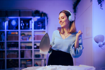 Happy Woman Dancing and Ironing Clothes Listening to Music. Cheerful carefree housewife doing...