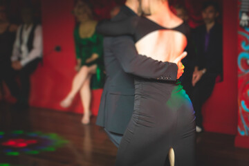 Couples dancing traditional latin argentinian dance milonga in the ballroom, tango salsa bachata kizomba lesson in the red and purple lights, festival, lesson class in dance school class academy