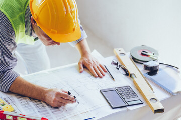 Architect Engineer Builder, Building Designer working with floorplan at Construction Site.