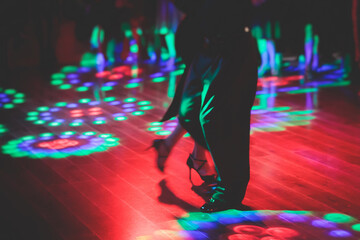 Couples dancing traditional latin argentinian dance milonga in the ballroom, tango salsa bachata kizomba lesson in the red and purple lights, festival, lesson class in dance school class academy