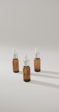 Vertical video of close up of three glass bottles with pumps on white background