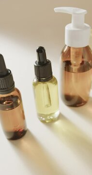 Vertical video of close up of glass bottles with pumps and copy space on beige background