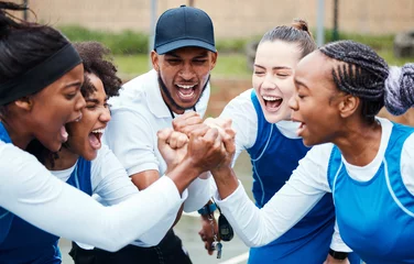 Fotobehang Fist, motivation or team support in netball training game screaming with hope or faith on sports court. Teamwork, fitness coach or group of excited athlete girls with pride or solidarity together © Anela R/peopleimages.com