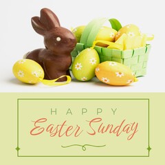 Image of happy easter sunday text over chocolate rabbit and easter eggs
