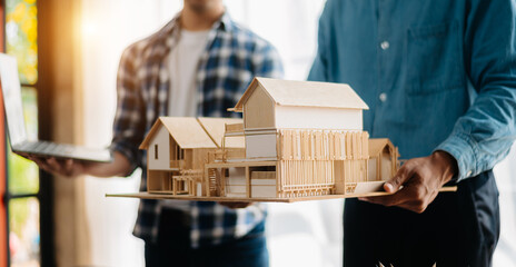 Close up shot of scale model house on table with architects. Two architects making architectural...