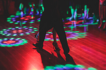 Couples dancing traditional latin argentinian dance milonga in the ballroom, tango salsa bachata kizomba lesson in the red and purple lights, festival, lesson class in dance school class academy