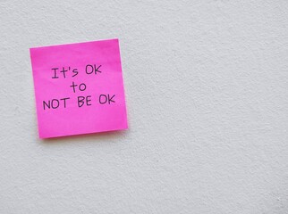 Torn note paper stick on red copy space background with text written IT'S OK TO NOT BE OK, means feelings and emotions expressing are valid no matter what they are, normal to say you are not okay