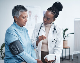 Black woman, doctor and senior patient with blood pressure reading for wellness, advice and conversation. Medic, elderly client and medical tools for health, cardiology and results in hospital office - Powered by Adobe