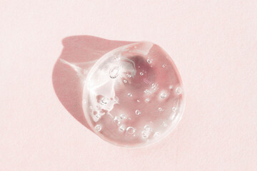 Transparent drop with bubbles on a pink background, top view. Cosmetic aloe vera gel for...