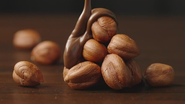 chocolate dripped to hazelnut.baking chocolate.pouring chocolate with hazelnut stack 
isolated on black. ingredient dessert liquid cacao .slow motion 4k