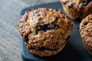 Delicious muffins with blueberries on a wooden table, closeup. Sweet pastries on the board. Fresh cupcakes for breakfast