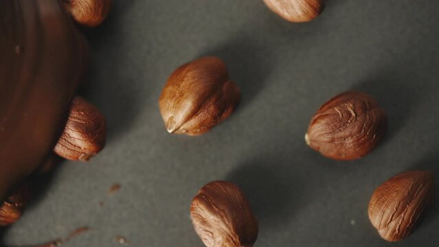 pouring chocolate on hazelnuts closeup slow liquid .4k footage
slowmotion melted chocolate
