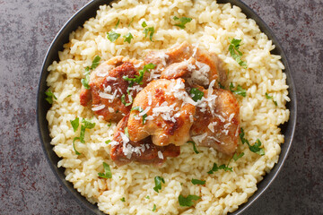 Delicious chicken risotto with parmesan and garlic closeup on the plate on the table. Horizontal top view from above