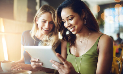 Our coffee dates are wherever we get free wifi. Cropped shot of girlfriends sharing something on a digital tablet while sitting in a cafe.