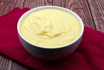 Mashed potatoes in white bowl on rustic table.