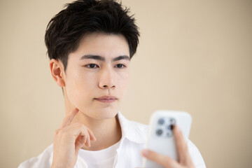 スマホを持って真剣な表情の若いハンサムな男性　アップ