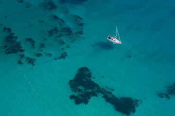 Sailing boat anchored on transparent blue water top view