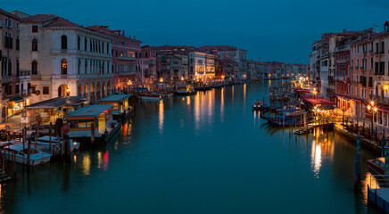 A canal in venice at night with lights on the buildings and boats on the water.