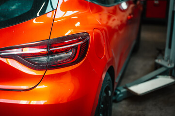 Modern red car parking in the car service. Close up. Headlights detail.