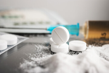 White pills, drugs or medical treatment, cocaine or heroin white powder, syringe with a dose and us...