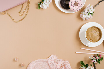 Stylish pale pink women's accessories, a cup of coffee and flowers on a beige background.