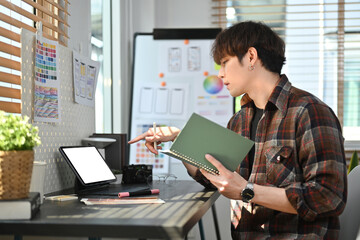 Stylish asian male Ux designer using digital tablet and planning new website wireframe at creative...