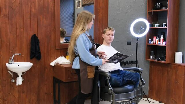 a young man with disabilities discusses a haircut with his master in a barbershop