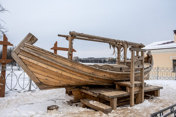 Fototapeta na wymiar an old wooden boat in the old center made according to the technologies of the past in Veliky Novgorod on a winter day