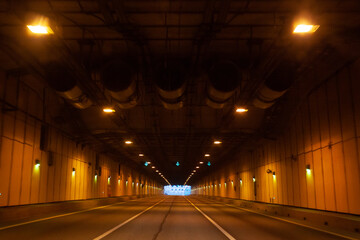 Empty long tunnel with yellow lamps on walls