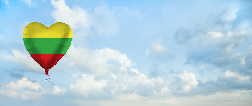 Flag of Lithuania on heart-shaped balloon against sky clouds background. Education, charity, emigration, travel and learning. Lithuanian language concept