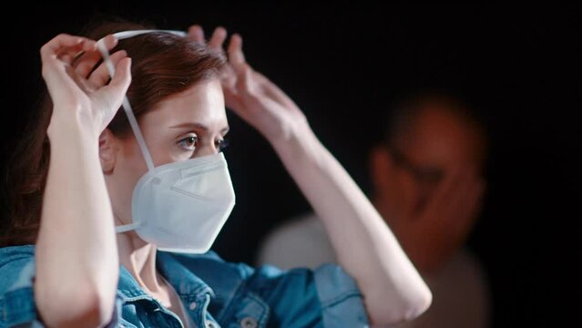 (Camera: ARRI ALEXA, real time) A young caucasian woman puts on her n95 mask while a man is coughing in the background. For more variations of this clip, check out this seller's other videos.
