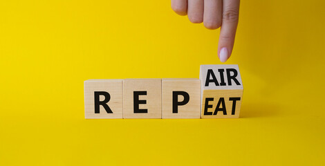 Repair and Repeat symbol. Businessman hand points at turned wooden cubes with words Repeat and Repair. Beautiful yellow background. Business and Repair and Repeat concept. Copy space