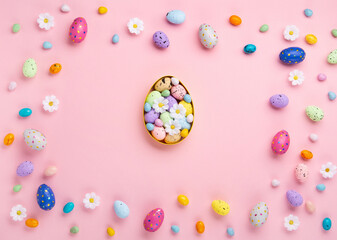 Easter Eggs with Sweets and Spring Flowers on Pink Background