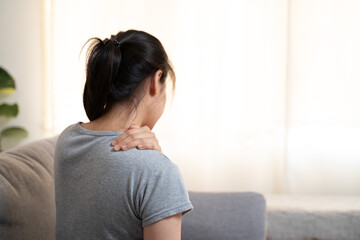 Tired woman touch stiff neck feeling hurt joint back pain rubbing massaging tensed muscles suffer from shoulder ache after long computer work study in incorrect posture sit on sofa at home - obrazy, fototapety, plakaty