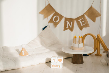 Photo zone for an anniversary or birthday with a mattress, wooden toys and a birthday cake.