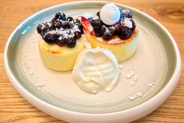 Syrniki,  fried Eastern Slavic quark (cottage cheese) pancakes, served with  sour cream and berries