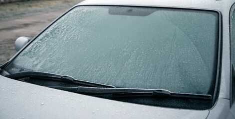 Obraz premium Frozen car on the outside parking. Transport in winter. Vehicle close-up with frozen windshield and windows.