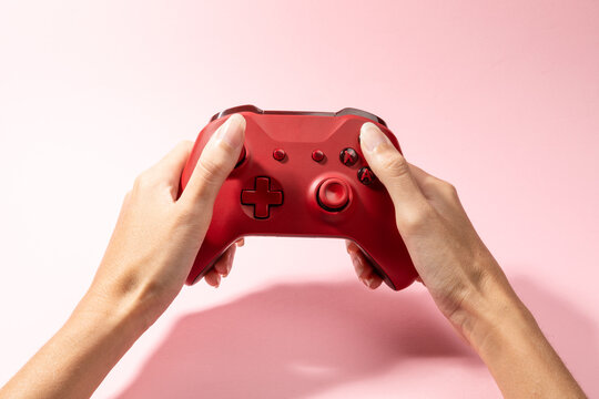 Woman's hand with gamepad controller on pink background