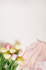 Women's clothing and a bouquet of spring bright tulip flowers on a beige background with a copy space. Flat lay concept of women's fashion, mother's day, birthday and spring