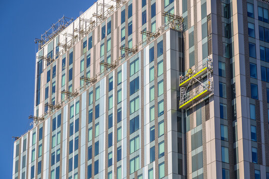 Construction workers inspecting / installing cladding on an apartment building in London, England
