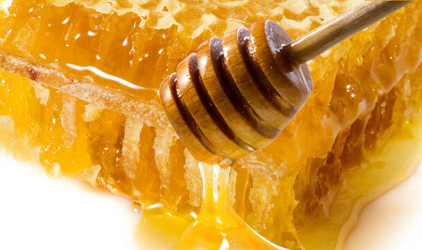  Honey with wooden dipper against white. Image of honey in honeycombs closeup