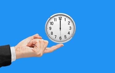 Classic clock in a human's hand on color background